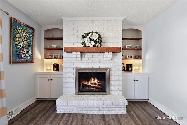 unfurnished living room with visible vents, built in shelves, a textured ceiling, and a fireplace