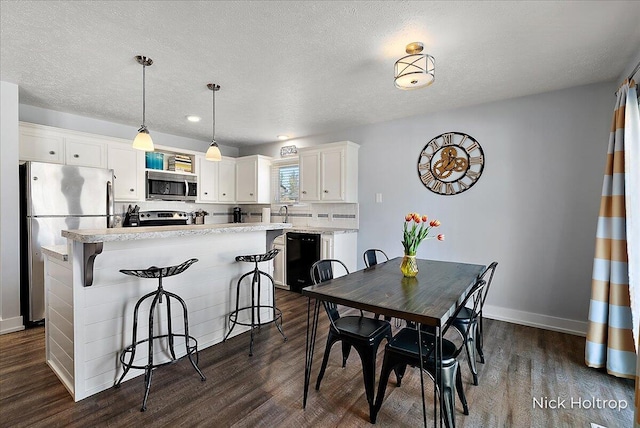 dining area featuring baseboards, a textured ceiling, and dark wood-style floors