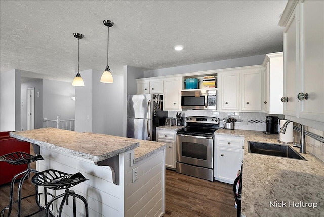 kitchen with a sink, dark wood-style flooring, white cabinetry, and stainless steel appliances