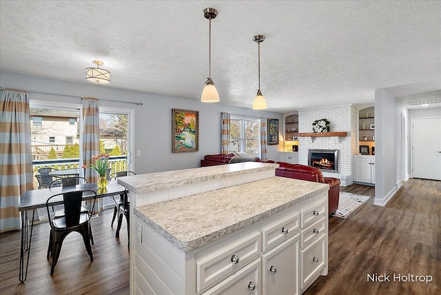 kitchen featuring light countertops, plenty of natural light, dark wood-style flooring, and a center island