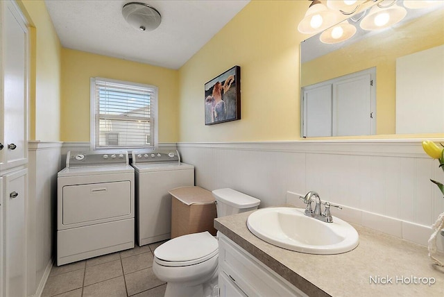 bathroom with a wainscoted wall, toilet, tile patterned floors, vanity, and separate washer and dryer