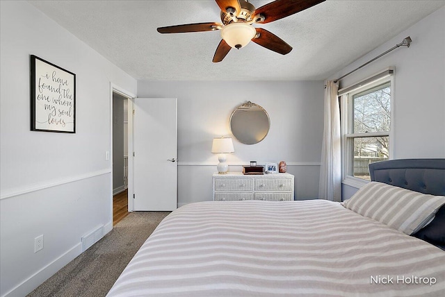 bedroom with visible vents, ceiling fan, baseboards, carpet flooring, and a textured ceiling