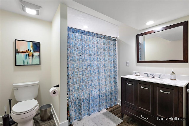 bathroom with toilet, curtained shower, wood finished floors, baseboards, and vanity