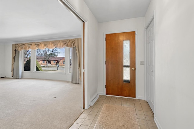 entryway featuring light tile patterned floors, light colored carpet, and baseboards