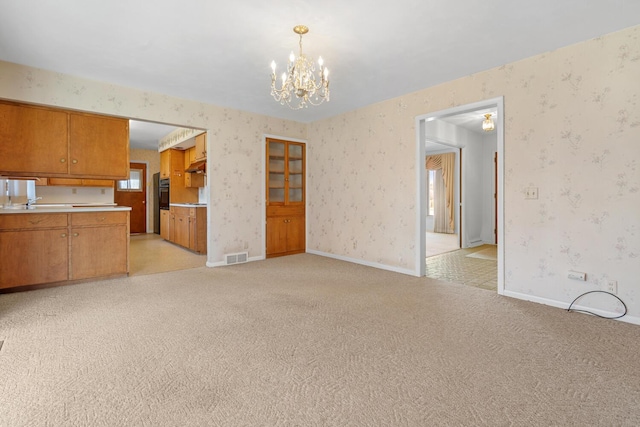 unfurnished living room with wallpapered walls, baseboards, and light carpet