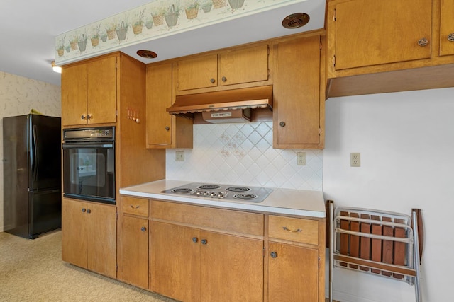 kitchen featuring under cabinet range hood, brown cabinets, black appliances, and light countertops