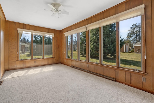 unfurnished sunroom featuring a baseboard heating unit and a ceiling fan