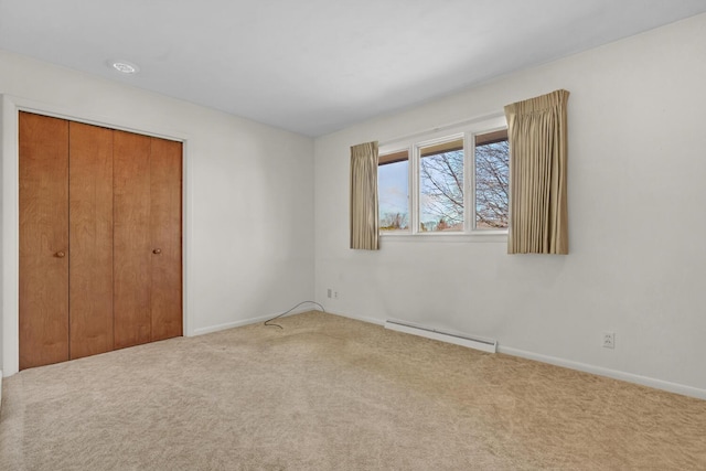 unfurnished bedroom featuring a closet, carpet floors, baseboard heating, and baseboards