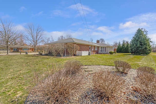 view of side of property featuring a lawn, brick siding, and a chimney