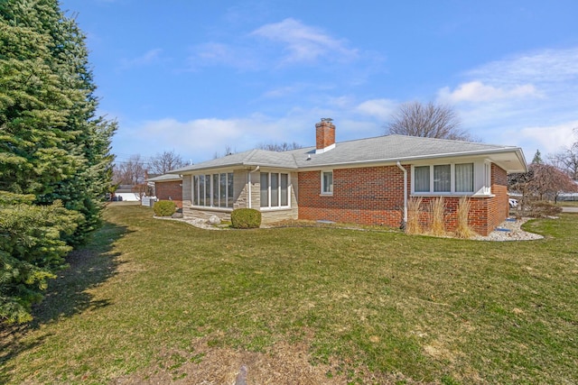 back of property with a yard, stone siding, brick siding, and a chimney