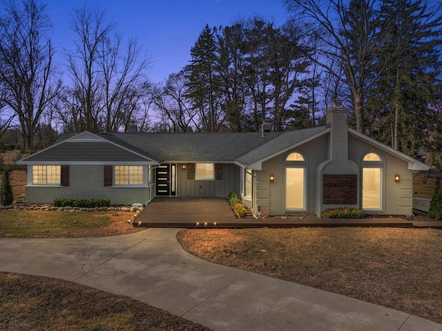 ranch-style home with brick siding, board and batten siding, concrete driveway, and a chimney