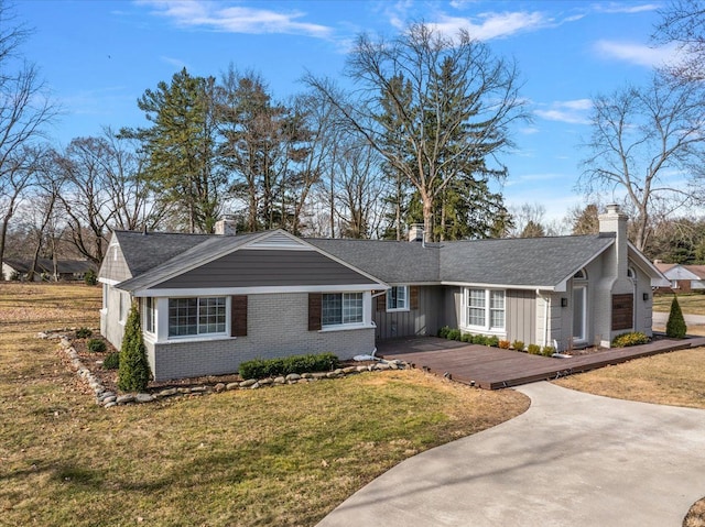 single story home featuring a front yard, driveway, brick siding, a chimney, and board and batten siding