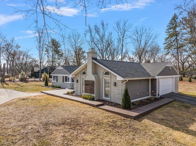 view of front facade with brick siding, an attached garage, a front yard, a chimney, and driveway