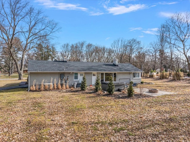 rear view of property featuring a patio, central AC, a fire pit, brick siding, and a hot tub