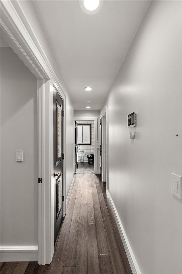 corridor with dark wood-style floors and baseboards