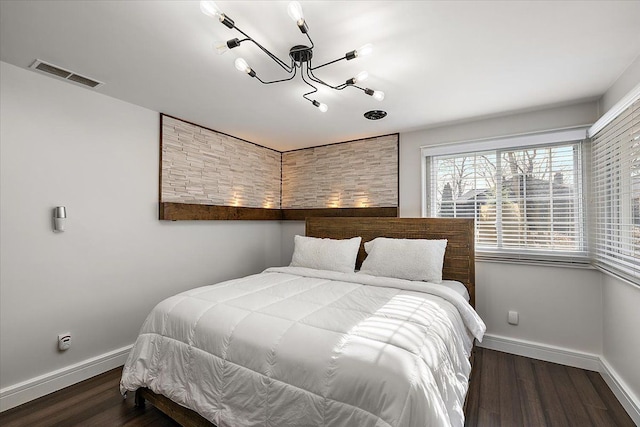 bedroom with visible vents, wood finished floors, baseboards, and a chandelier