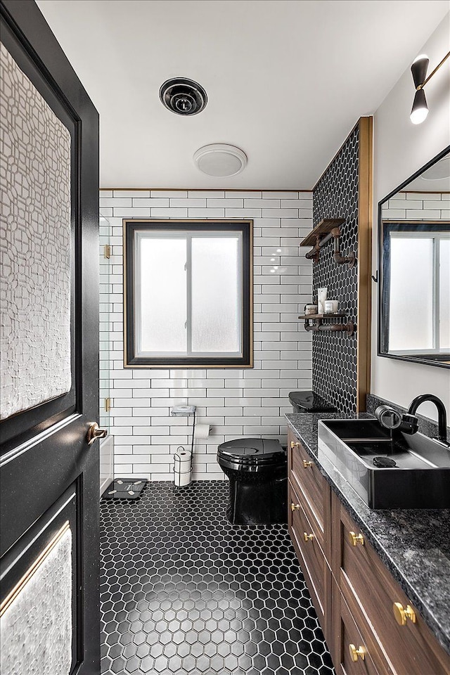 bathroom with visible vents, tile walls, toilet, plenty of natural light, and vanity