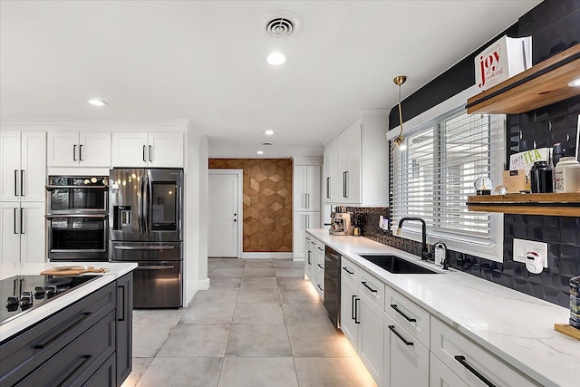 kitchen featuring visible vents, black appliances, a sink, backsplash, and white cabinets