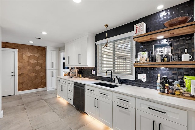 kitchen with a sink, open shelves, black dishwasher, white cabinets, and light stone countertops