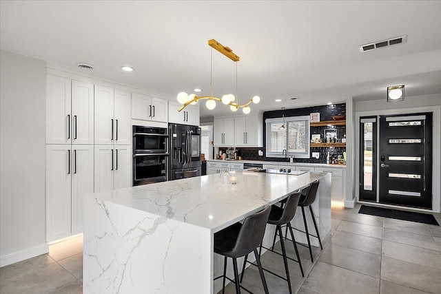 kitchen with black appliances, white cabinets, and visible vents