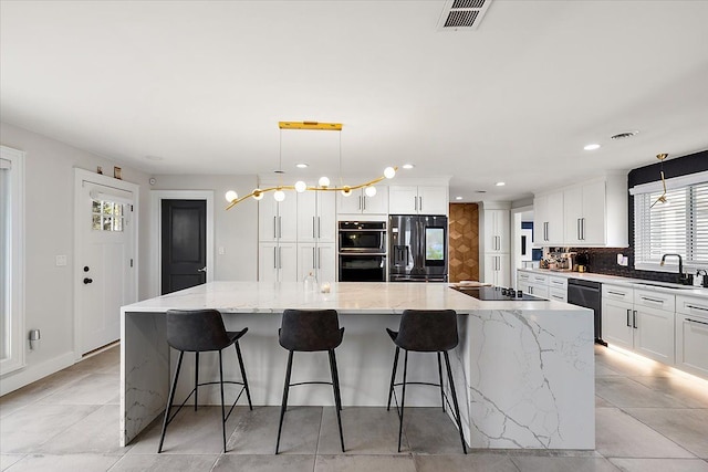 kitchen with a large island, black appliances, a sink, backsplash, and white cabinets