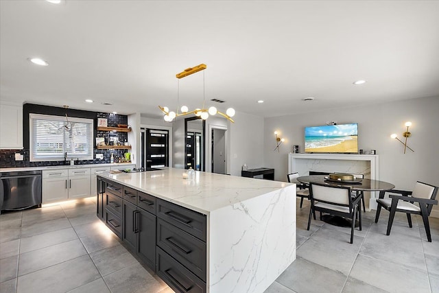 kitchen with tasteful backsplash, a kitchen island, dishwasher, light stone counters, and white cabinets