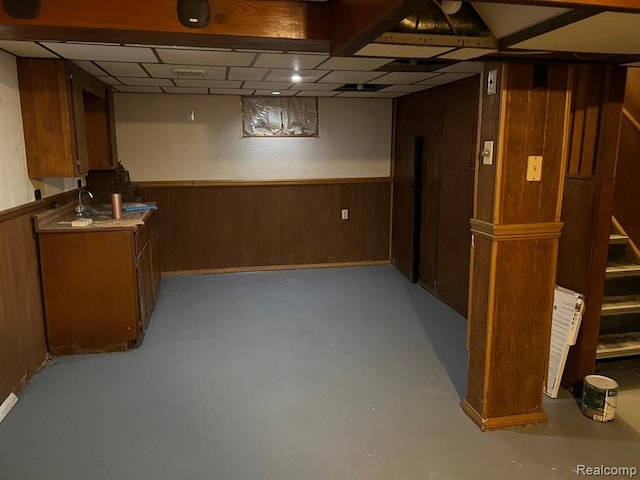 finished basement featuring a sink, visible vents, wood walls, and wainscoting