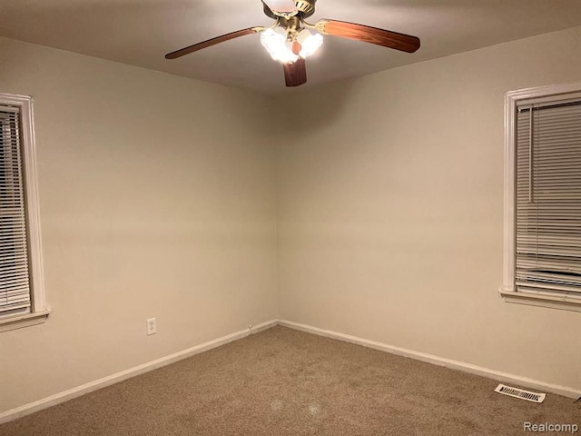 carpeted empty room with baseboards, visible vents, and ceiling fan