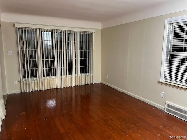 unfurnished room featuring wood finished floors, visible vents, and baseboards