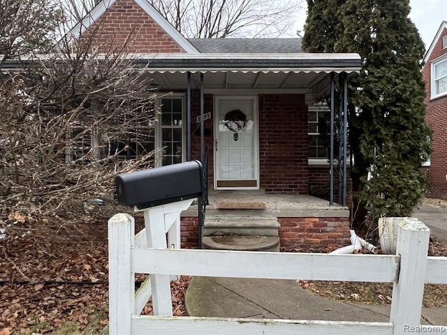 view of front facade featuring a porch, brick siding, and roof with shingles