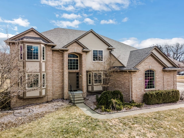 view of front of house featuring brick siding and roof with shingles