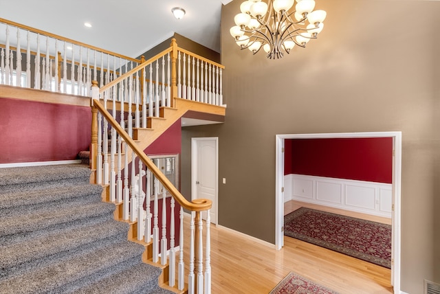 staircase featuring visible vents, a wainscoted wall, a notable chandelier, wood finished floors, and recessed lighting