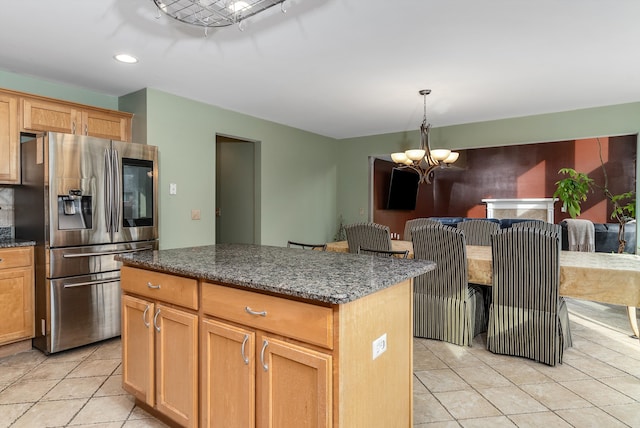 kitchen featuring dark stone countertops, decorative light fixtures, a notable chandelier, stainless steel fridge, and a center island