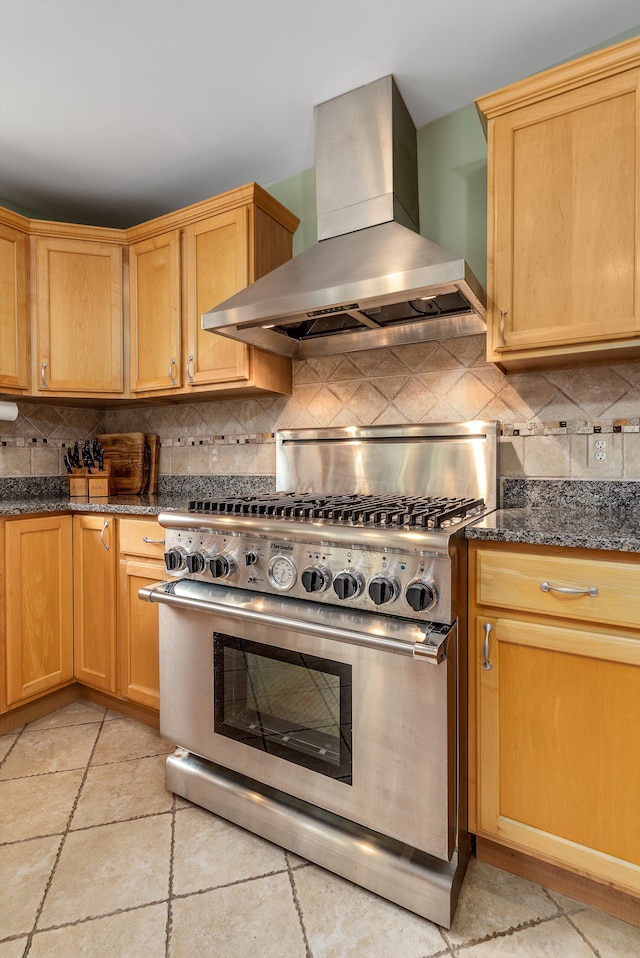 kitchen featuring decorative backsplash, stainless steel stove, exhaust hood, and dark stone counters