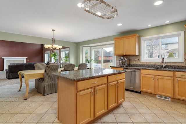 kitchen with visible vents, a sink, dishwasher, backsplash, and a center island