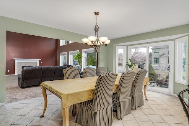 dining area with baseboards, a notable chandelier, light tile patterned flooring, and a fireplace