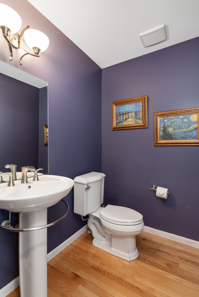 bathroom with toilet, baseboards, and wood finished floors