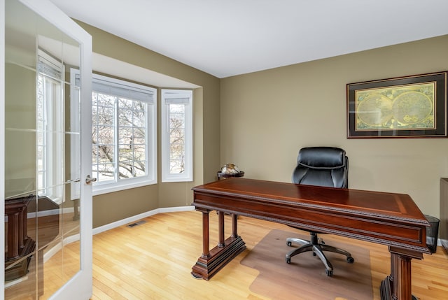 office area with light wood-style flooring, baseboards, and visible vents