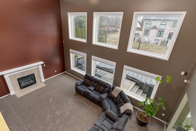 carpeted living area with a healthy amount of sunlight, baseboards, and a tile fireplace