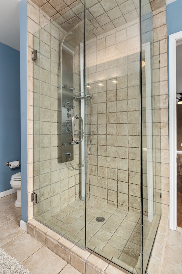 full bath featuring tile patterned flooring, a shower stall, toilet, and baseboards