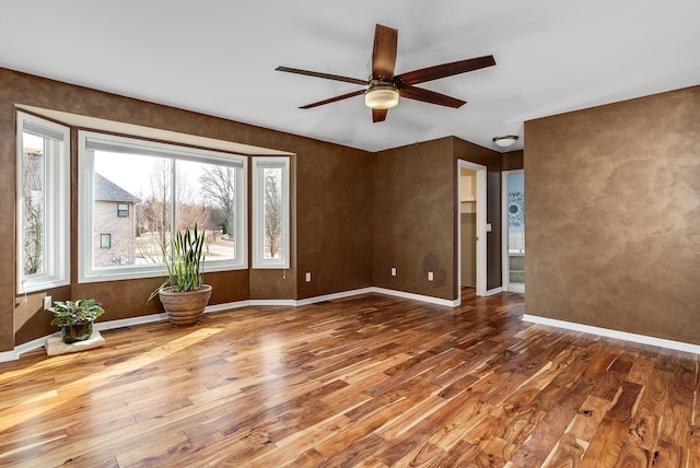 unfurnished room with a ceiling fan, baseboards, and wood finished floors