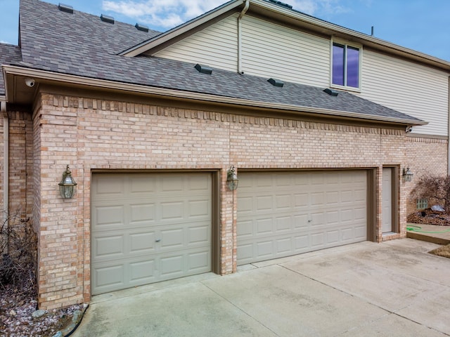 view of side of property featuring driveway, brick siding, an attached garage, and a shingled roof