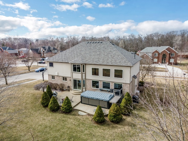 rear view of house featuring a patio area, brick siding, a lawn, and a shingled roof