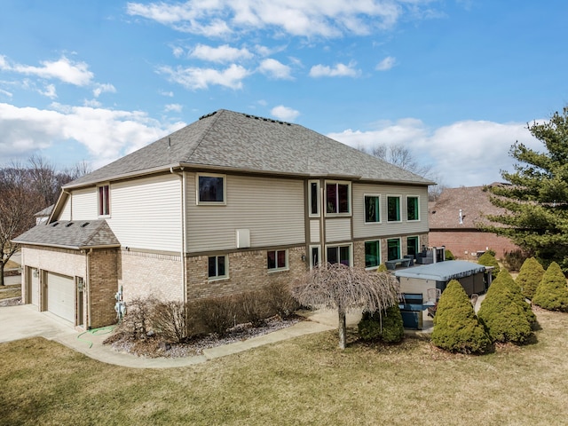 back of house with a yard, brick siding, driveway, and roof with shingles