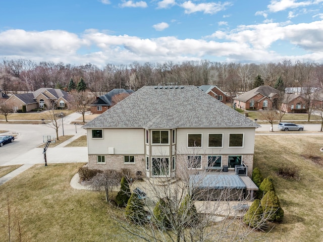 back of house with a yard, a residential view, brick siding, and roof with shingles