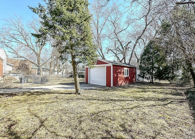 view of yard with a garage, concrete driveway, an outdoor structure, and fence