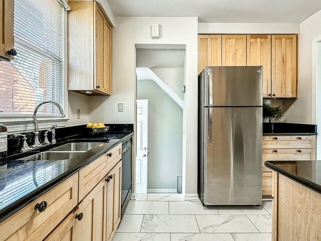 kitchen with light brown cabinetry, marble finish floor, freestanding refrigerator, and a sink