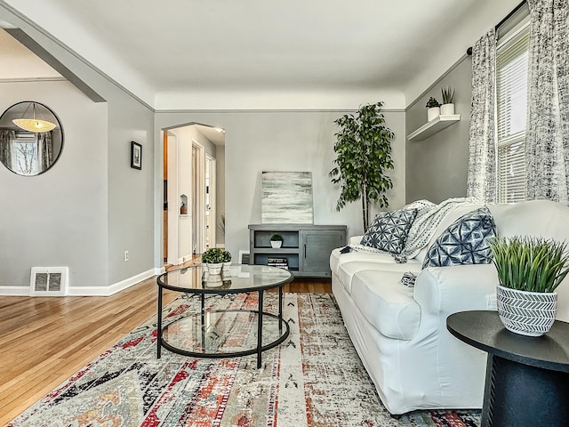 living room with visible vents, baseboards, and wood finished floors