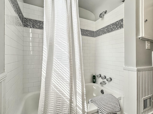 bathroom featuring a wainscoted wall and shower / bath combo with shower curtain