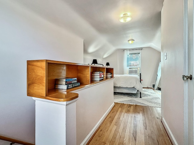 bedroom with cooling unit, hardwood / wood-style flooring, baseboards, and vaulted ceiling